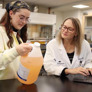 Lily Eggert and Dr. Alexandra Weissfloch examine a jar of boat cleaner.