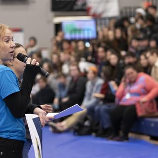 A student speaks into a microphone in front of a crowd