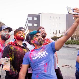 A group of students with coloured chalk on them pose for a selfie