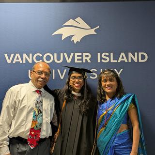 Three people in front of the VIU logo