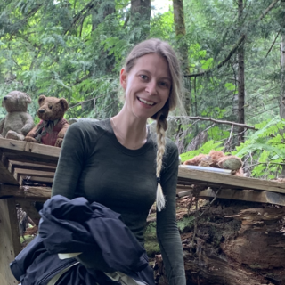 Isabelle Desrosiers in a green forest and smiling at the camera.