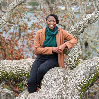 Smiling Black Woman sitting on a downed tree branch