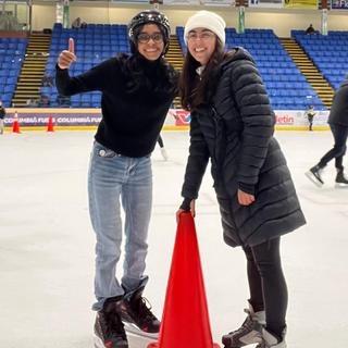 Two people on ice skates with a cone in between them