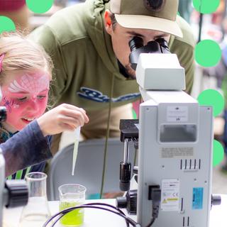 A dad and his daughter look into a microscope