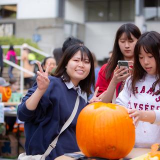 three students carve a pumpkin together