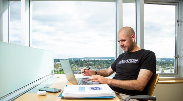 Student studies at a desk in the library with a view of the City of Nanaimo in the background