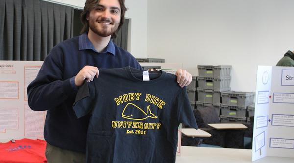 A student holds up a sweater that reads Moby Dick University