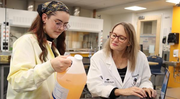 Lily Eggert and Dr. Alexandra Weissfloch examine a jar of boat cleaner.