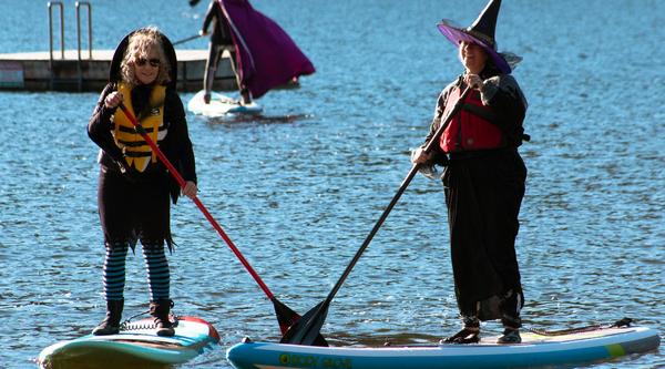 Two women dressed as witches paddle on Westwood Lake