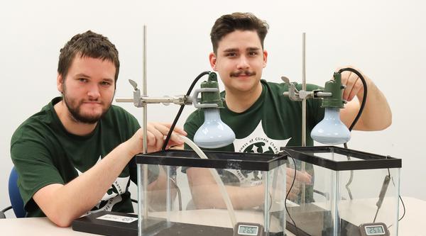 Kyle Wickland and Oscar Thoms have two glass tanks in front of them with thermometers and temperature gauges.
