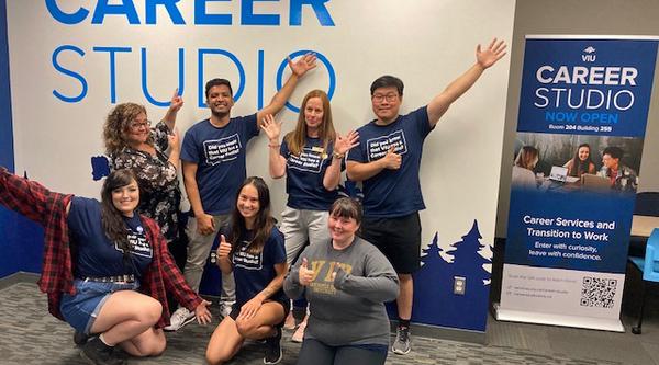 A group poses with the Career Studio sign and banner