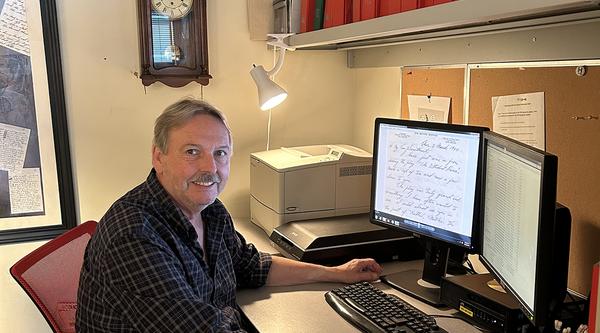 Dr. Stephen Davies sits in front of his computer, which displays a digitized letter