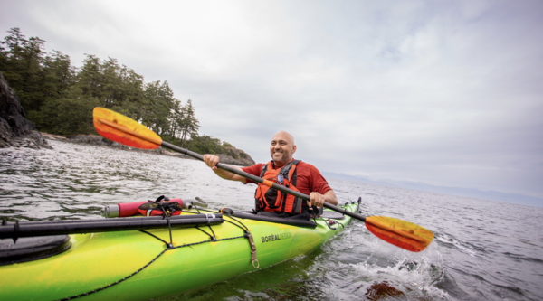 Farhad Moghimefar paddling a kayak and smiling off into the distance