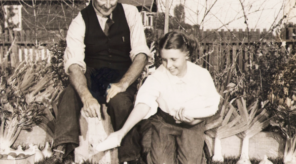 A man and a woman kneel behind produce laid out on grass