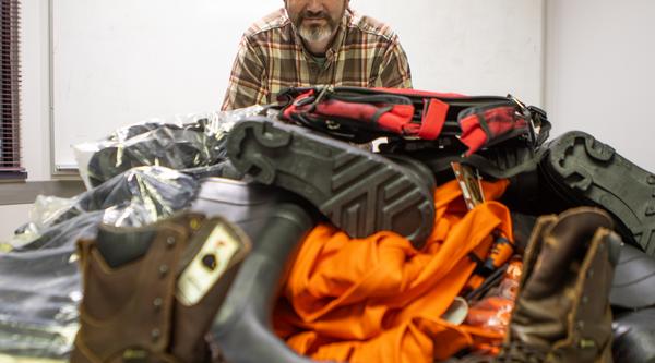 Mike with boots, waterproof jackets and waders laid out on a table