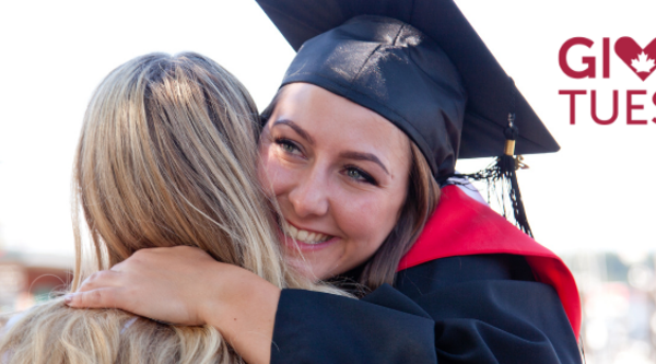 Student in grad cap hugs someone with words Giving Tuesday on side