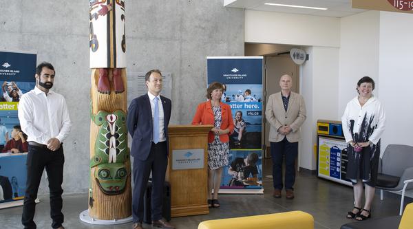 Five people stand in VIU's Health and Science Centre during a media conference.