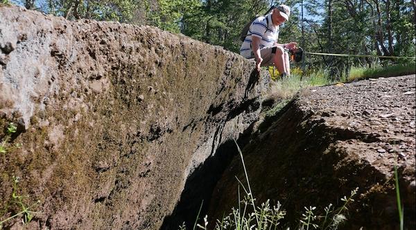 A man sits and observes a large crack in the ground