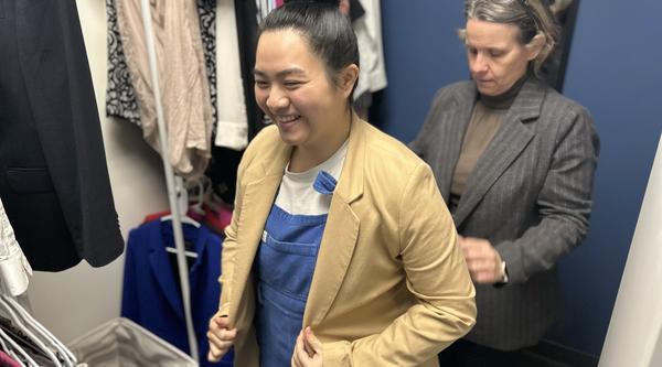 One woman helps another try on a blazer