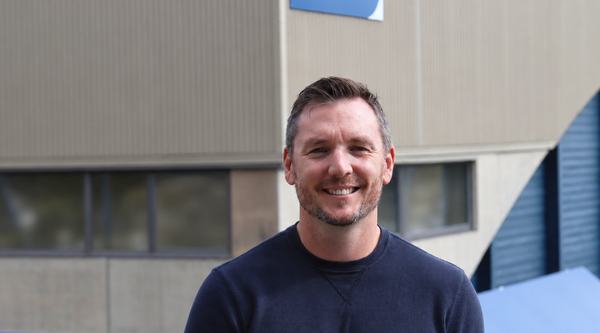 Jordan Herbison standing outside the VIU gym in a sunny day and smiling.