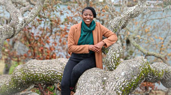 Smiling Black Woman sitting on a downed tree branch