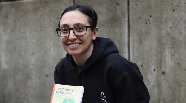 Lauren Touchant sitting outside and displaying her book and smiling at the camera.