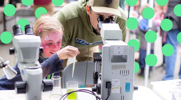 A dad and his daughter look into a microscope