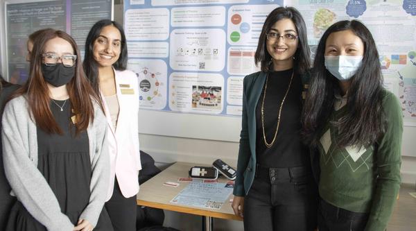 Four students standing in front of a poster