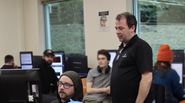 Information Technology and Applied Systems Instructor Brandon Britt observes carl belie on a project. 