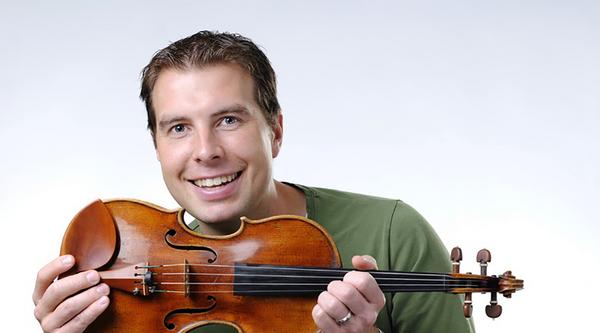 James Mark smiles while holding a violin.