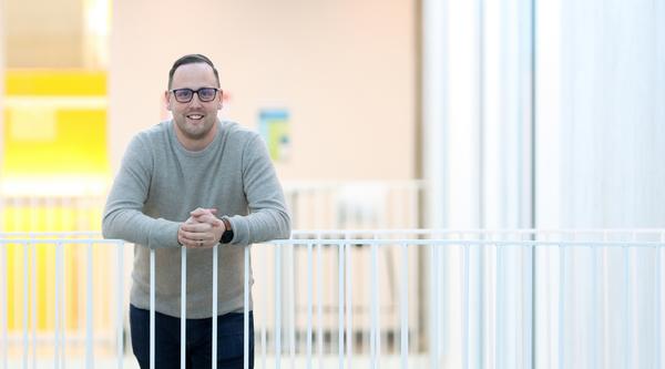 Dr. Kyle Duncan, a VIU Chemistry Professor,  smiles while leaning against a white railing.