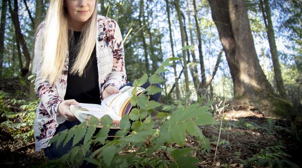 Mandy Hobkirk uses an identification book while examining plants at VIU's Nanaimo Campus.