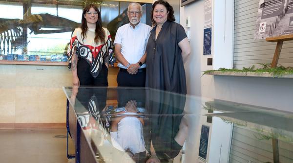 Three people pose with a tank