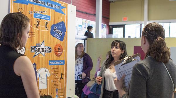 Three students examine a research poster at CREATE.