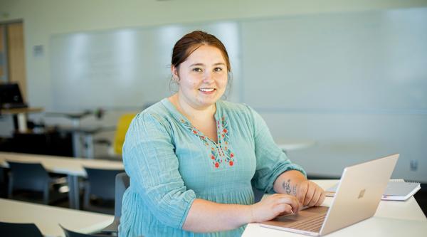Sarah types on a laptop in a classroom