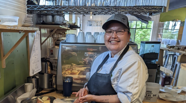 VIU Culinary Arts student Darlene Charlie making a sandwich in the Birch Tree cafe kitchen and smiling at the camera