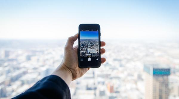 person holding cellphone out to take a picture of a city view