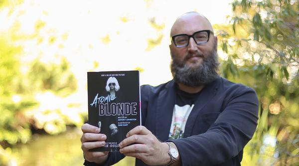 Theo Finigan holds out a copy of the book Atomic Blonde 