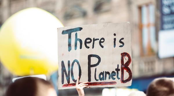 Hands holding a sign that reads: There is no Planet B