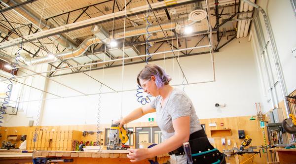 Female cutting a board in carpentry shop