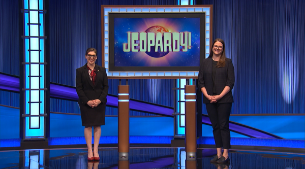 Whitney Wood stands on the Jeopardy! stage with host Mayim Bialik.