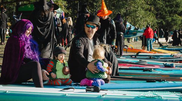 People dressed in costumes sitting on paddleboards at Westwood Lake