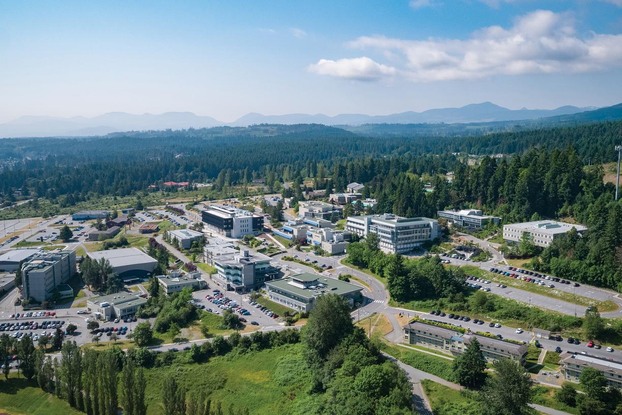 Ariel photograph of the Vancouver Island University campus with several buildings on a hillside on a sunny day