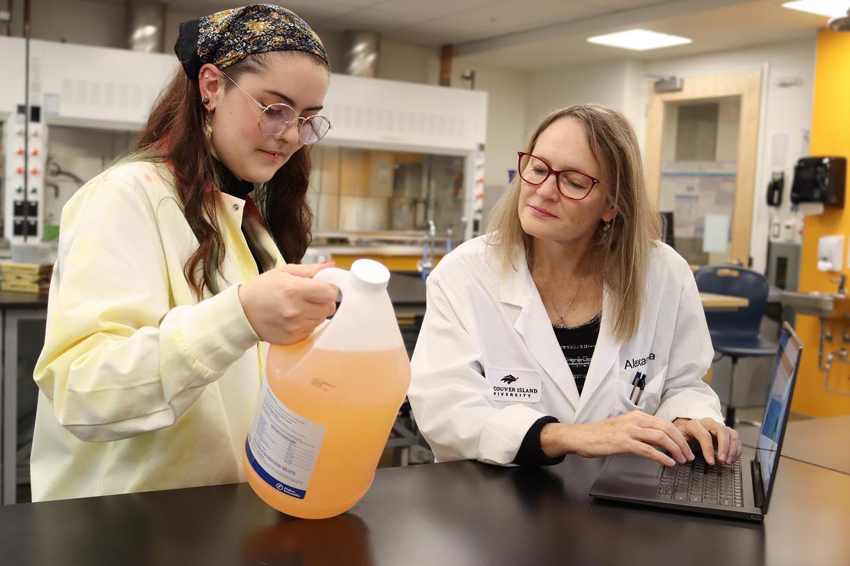 Lily Eggert and Dr. Alexandra Weissfloch examine a jar of boat cleaner.