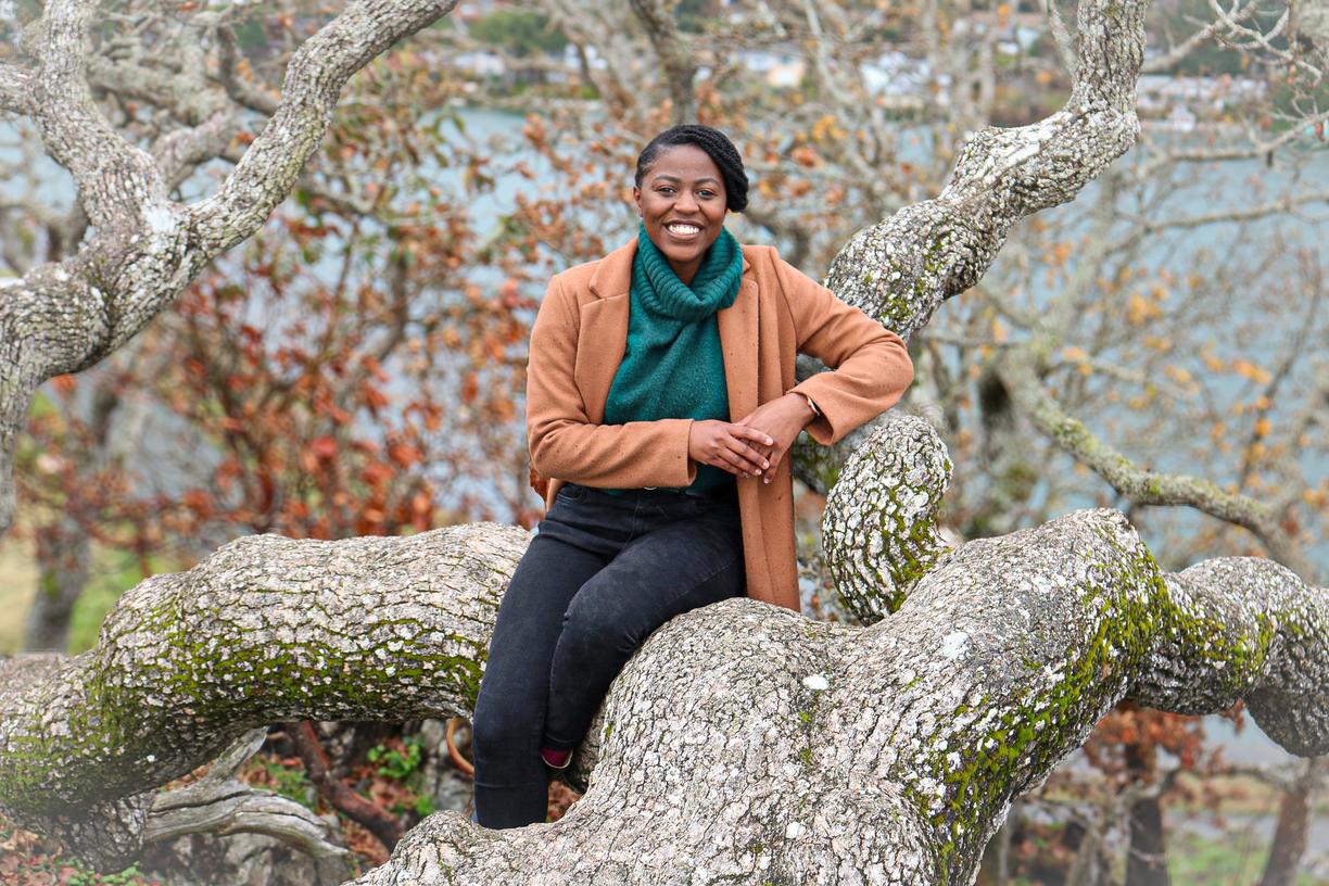 Smiling Black Woman sitting on a downed tree branch