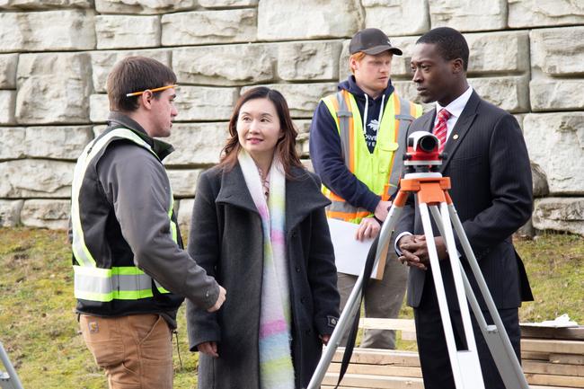 Four people chat and look at surveying equipment together