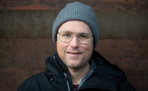 a headshot of trevor wideman, who is wearing a jacket, toque and glasses