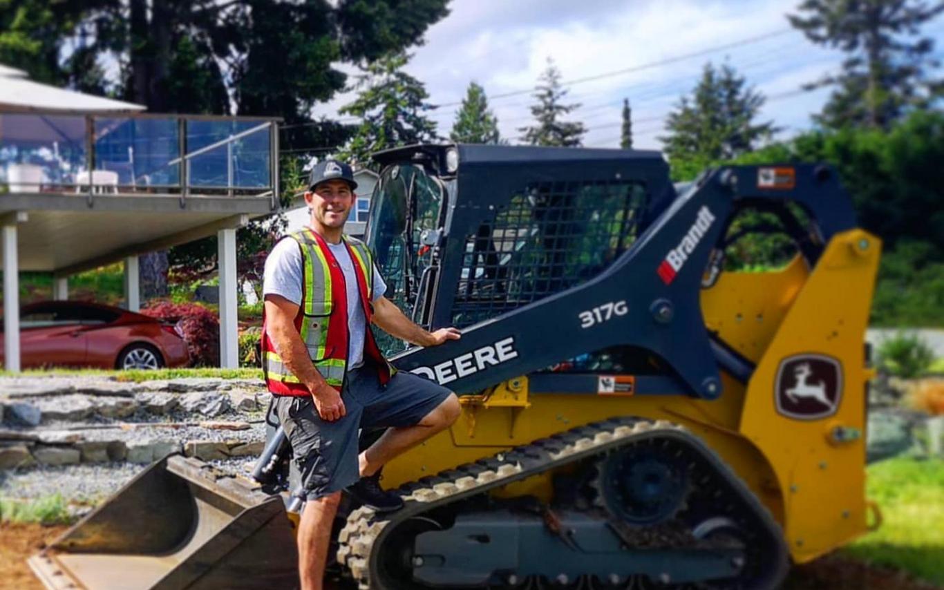 Jesse Anderson standing outside in front of one of his machines on a sunny day.