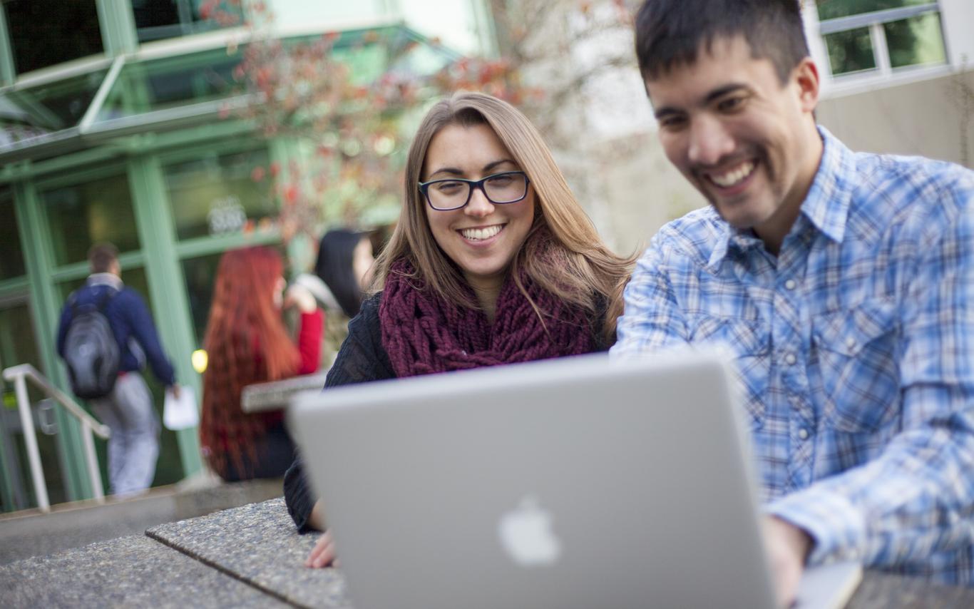 Two students look at a laptop screen together