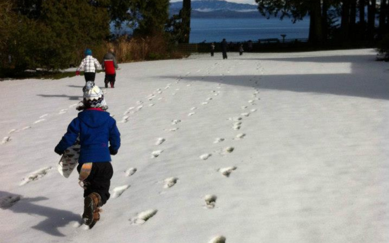Children running across a snowy lawn